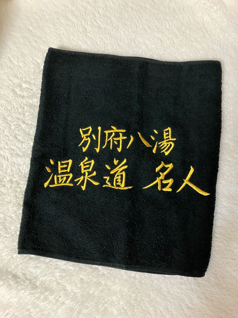 別府八湯温泉道名人の刺繍が入っている黒いタオル